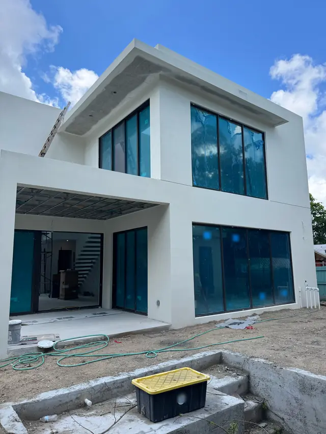 Casa blanca de dos pisos con ventanas y puertas de impacto instaladas