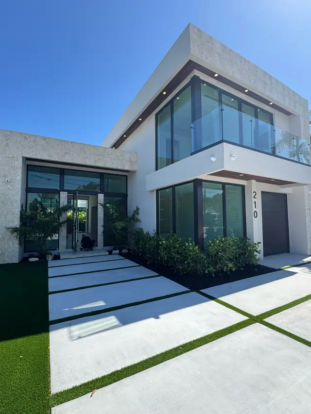 Casa moderna de dos pisos terminada con grandes ventanas y puertas de vidrio de impacto