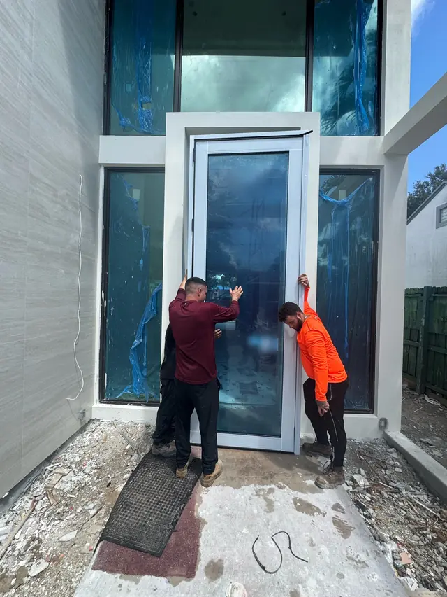 Instaladores de Mora Glass Windows colocando una puerta de impacto