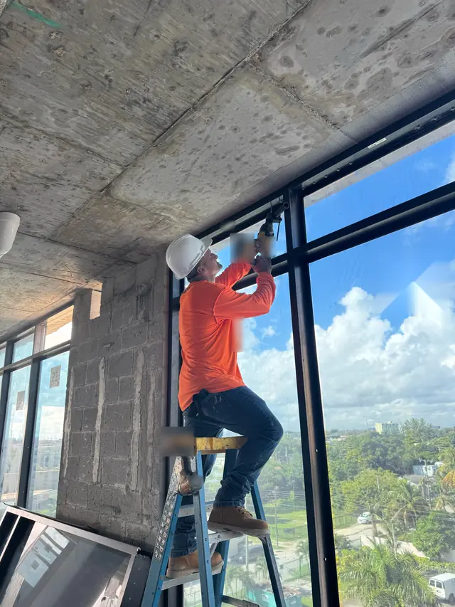 Instalador de Mora Glass Windows ajustando una ventana de impacto en un piso alto