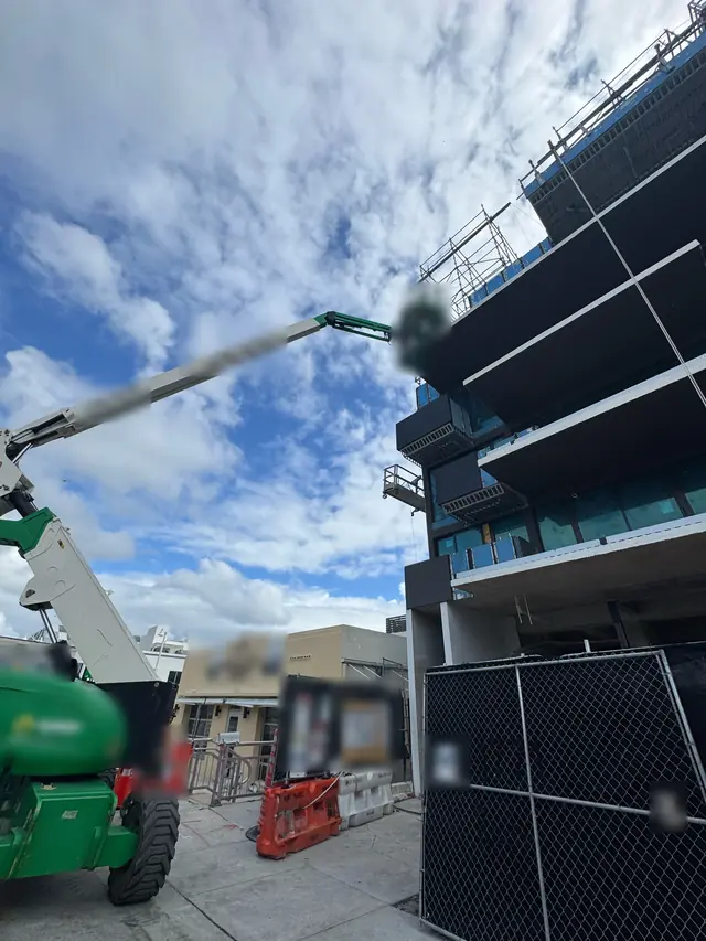 Obra comercial con plataforma elevadora para instalar ventanas de impacto en altura